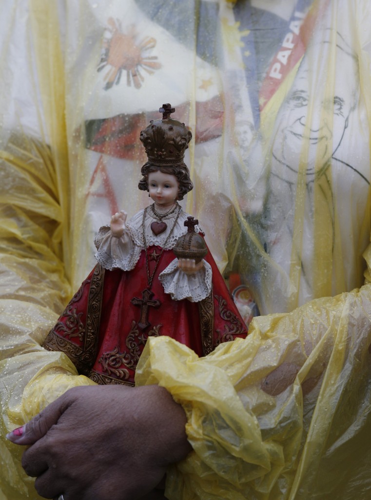 Woman holds statue of statue of Santo Nino as Pope Francis celebrates Mass at Rizal Park in Manila, Philippines