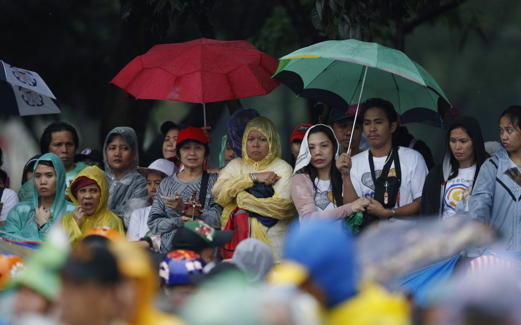 People wait to see Pope Francis along his motorcade route after Mass in Rizal Park in Manila