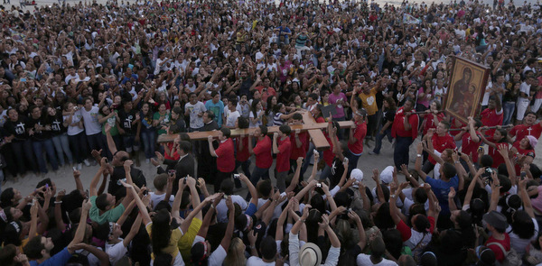 Young people carry the World Youth Day cross during its arrival at a beach in Rio de Janeiro