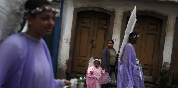 Child dressed as angel walks alongside women during Easter Sunday procession in Brazil