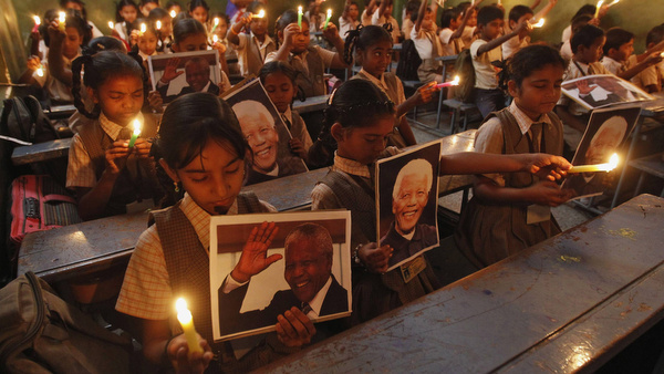 Schoolchildren hold candles and portraits of former South African President Mandela during prayer ceremony in India