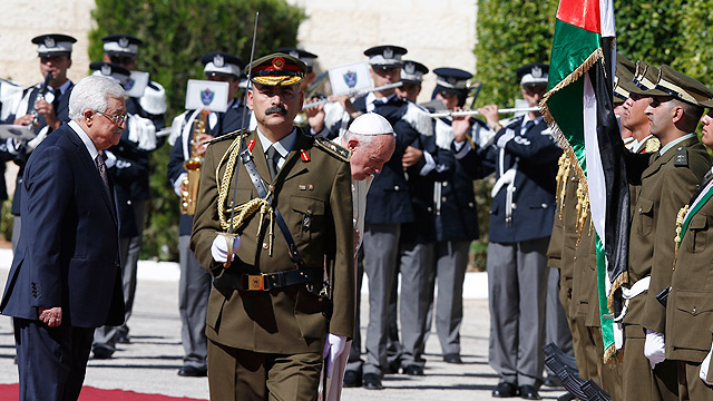 Pope Francis bows towards the flag of the Palestinian Authority as he reviews the honor guard during an arrival ceremony with Palestinian President Mahmoud Abbas, left, at the presidential palace in Bethlehem, West Bank, May 25. (CNS photo/Paul Haring) 