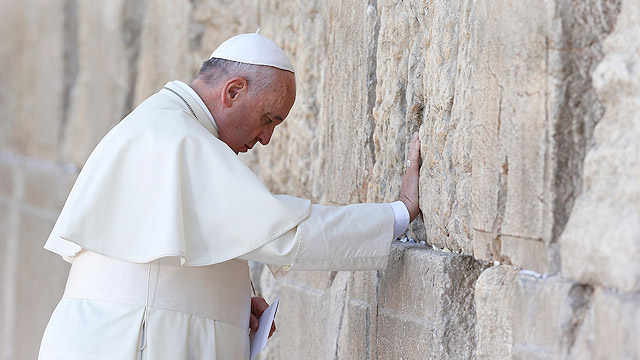 Pope Francis prays at the Western Wall in Jerusalem May 26. The pope stood for more than a minute and a half with his right hand against the wall, most of the time in silent prayer, before reciting the Our Father. Then he followed custom by leaving a wri tten message inside a crack between two blocks. (CNS photo/Paul Haring)