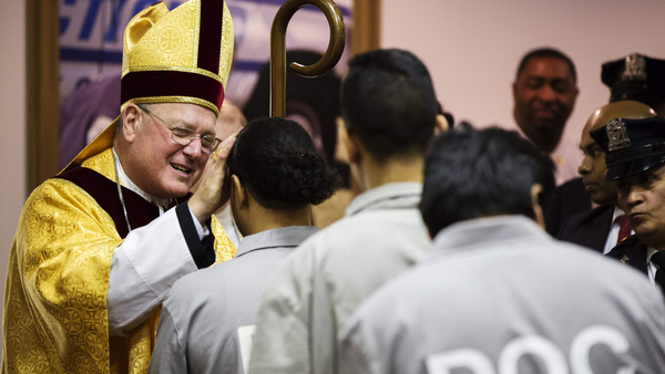 New York Cardinal Timothy M. Dolan blesses an inmate as he celebrates Christmas Eve Mass at Rikers Island correctional facility in New York Dec. 24. (CNS photo/Lucas Jackson, Reuters) (Dec. 26, 2013)