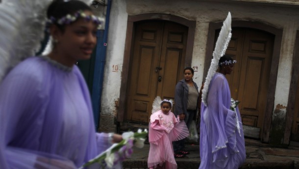 Child dressed as angel walks alongside women during Easter Sunday procession in Brazil