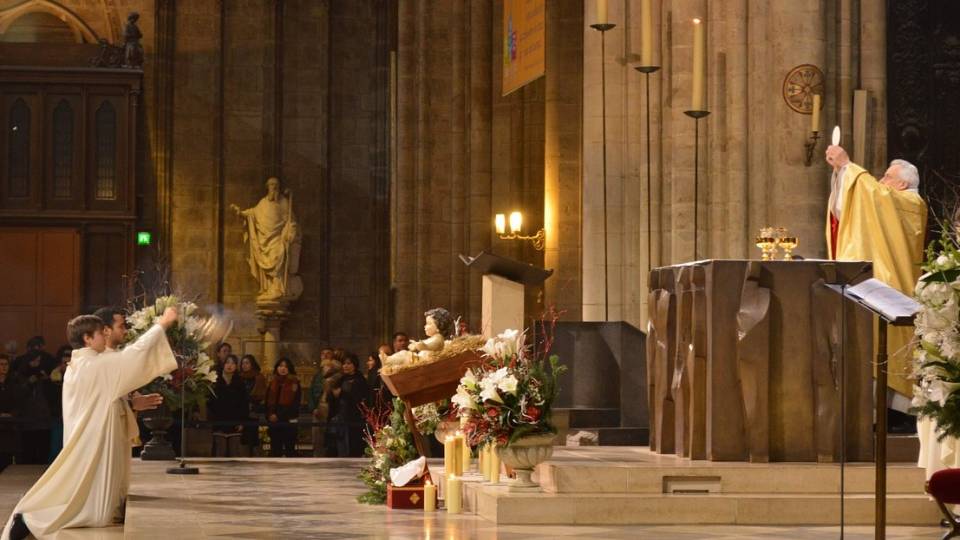 A priest elevates the host in Notre Dame Cathedral in Paris