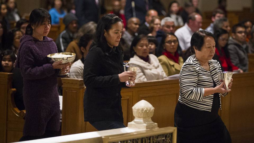 Women bring offertory gifts to the altar during Mass