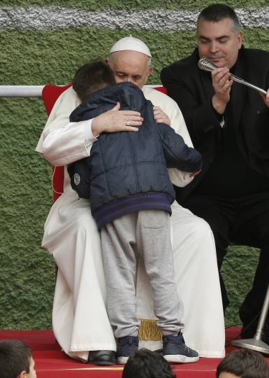 Pope Francis embraces Emanuele, a boy whose father died, as he visits St. Paul of the Cross Parish in Rome April 15. (CNS photo/Paul Haring)