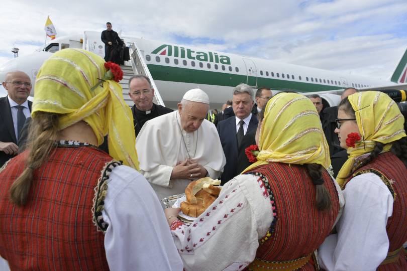 Pope Francis accepts gifts from women in traditional dress as he arrives at the international airport in Skopje, North Macedonia, May 7, 2019. (CNS photo/Vatican Media)