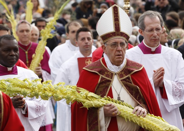 Pope Francis carries palm fronds as he walks in Palm Sunday procession at Vatican